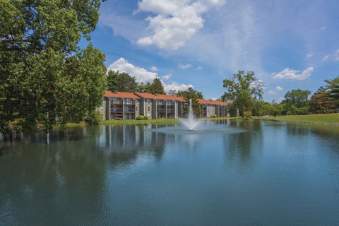 a fountain in the middle of a lake with a building in the background